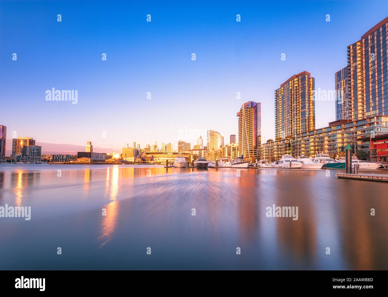 Illuminated buildings by river at Melbourne Docklands against blue sky at dusk, Victoria, Australia Stock Photo