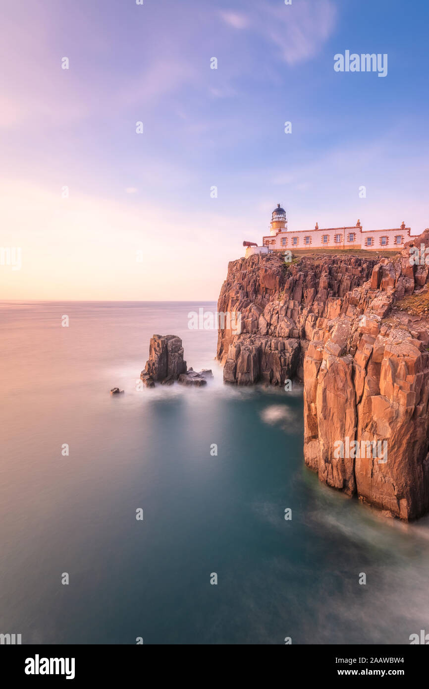 Neist Point Lighthouse by sea against sky during sunset at Waterstein, Isle of Skye, Highlands, Scotland, UK Stock Photo