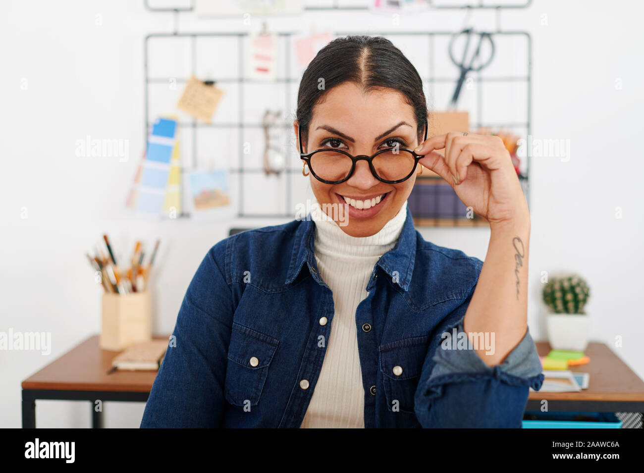 Young smiling woman with hand on glasses Stock Photo