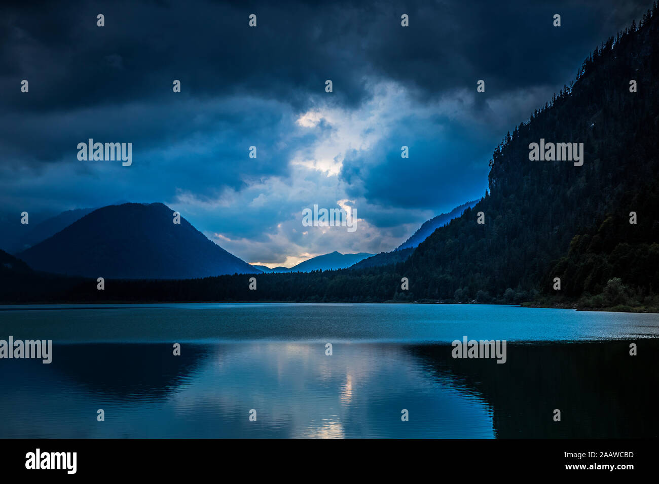 Scenic view of Sylvenstein Lake and silhouette mountains against cloudy sky, Bavaria, Germany Stock Photo