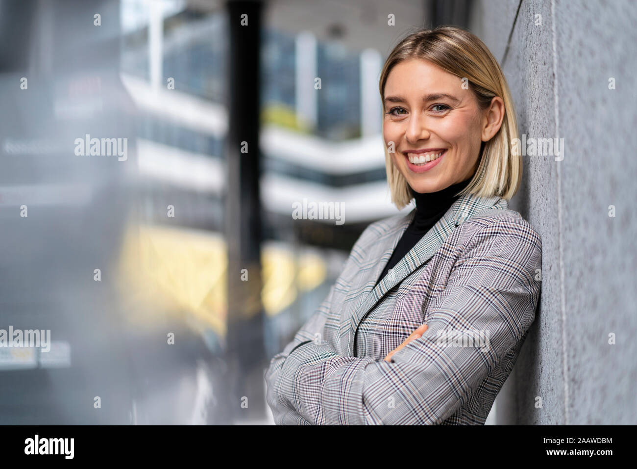 Portrait of confident young businesswoman leaning against a wall Stock Photo