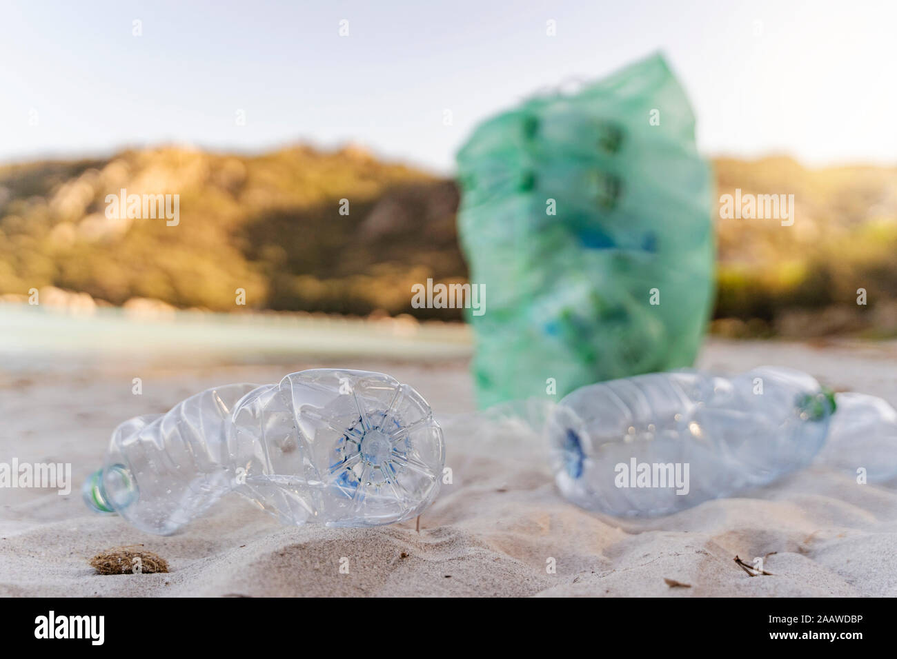 Empty plastic bottles and garbage bin full of collected plastic bottles on the beach Stock Photo