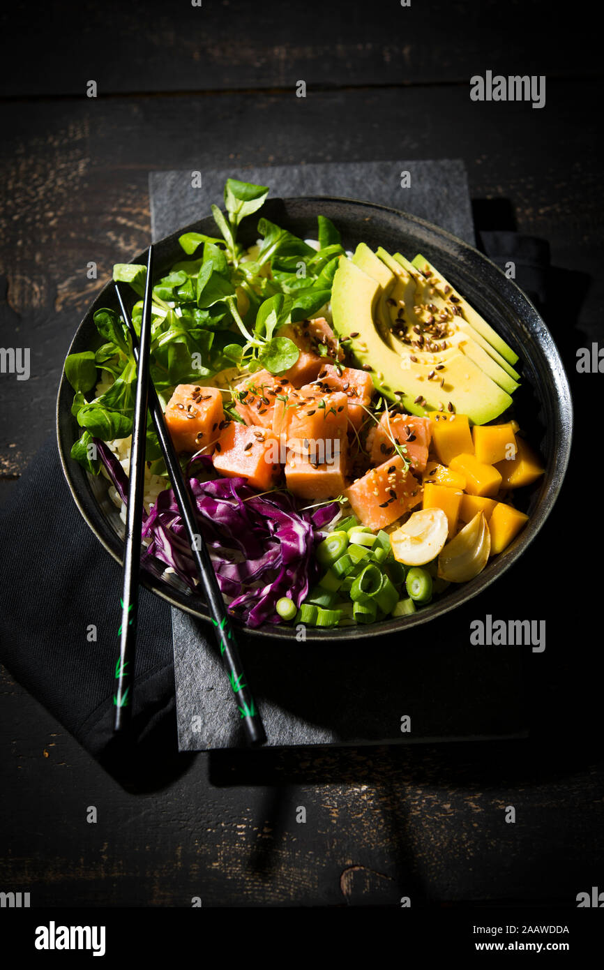 High angle view of poke bowl with chopsticks on wooden table Stock Photo