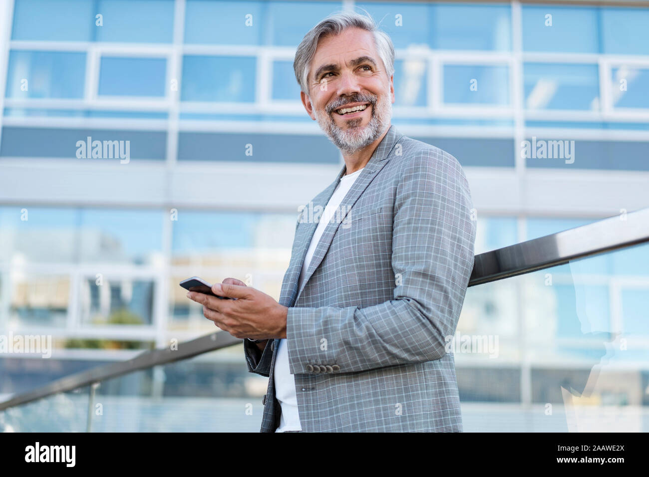 Smiling mature businessman with cell phone outdoors Stock Photo