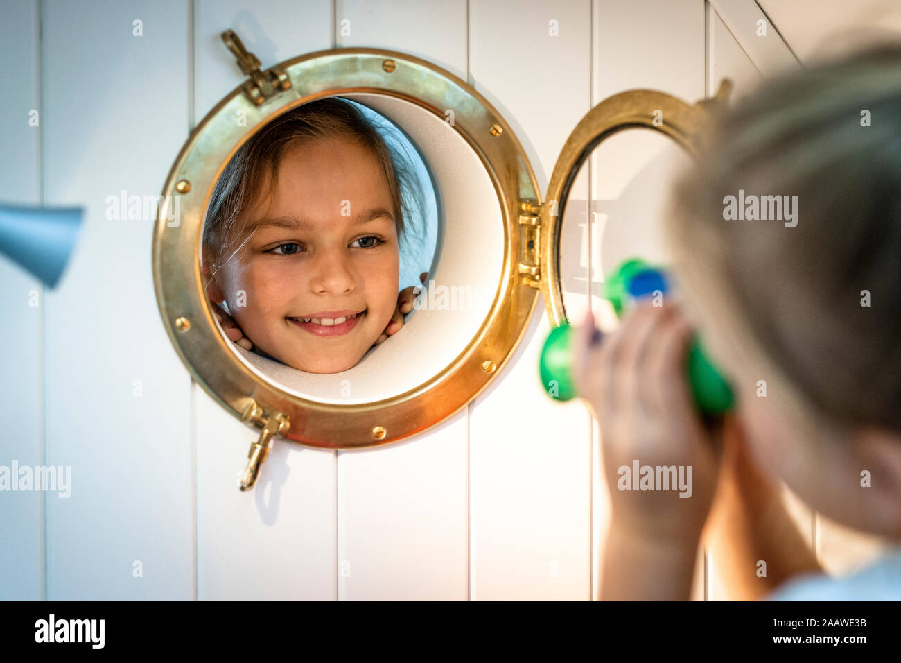 Smiling girl looking through porthole Stock Photo