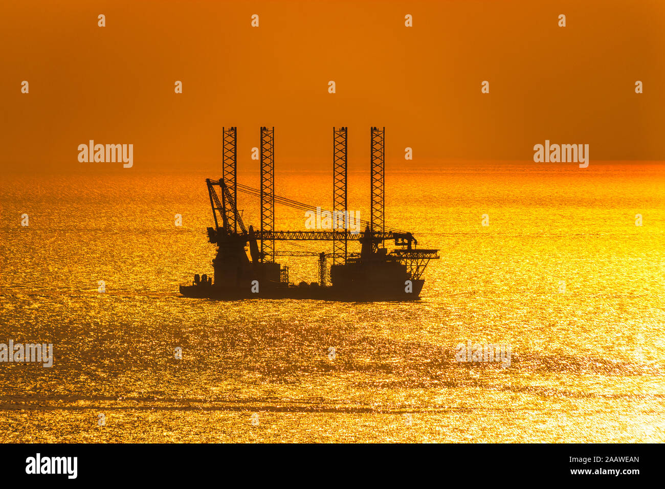 Silhouette offshore wind farm installation vessel sailing off in sea against sky during sunset, West Coast, Scotland, UK Stock Photo