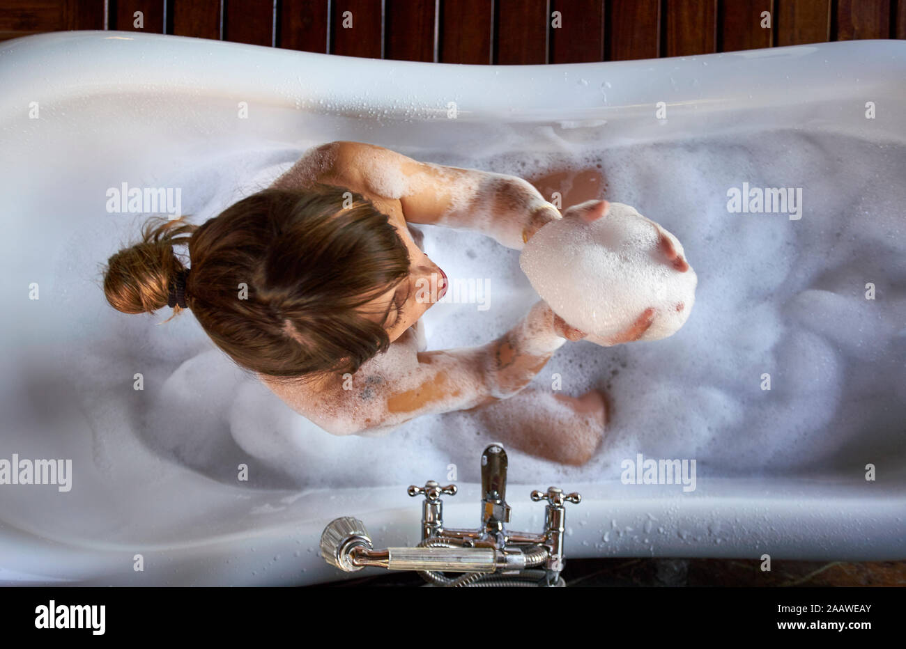 Woman playing with the foam in a bathtub, from above Stock Photo