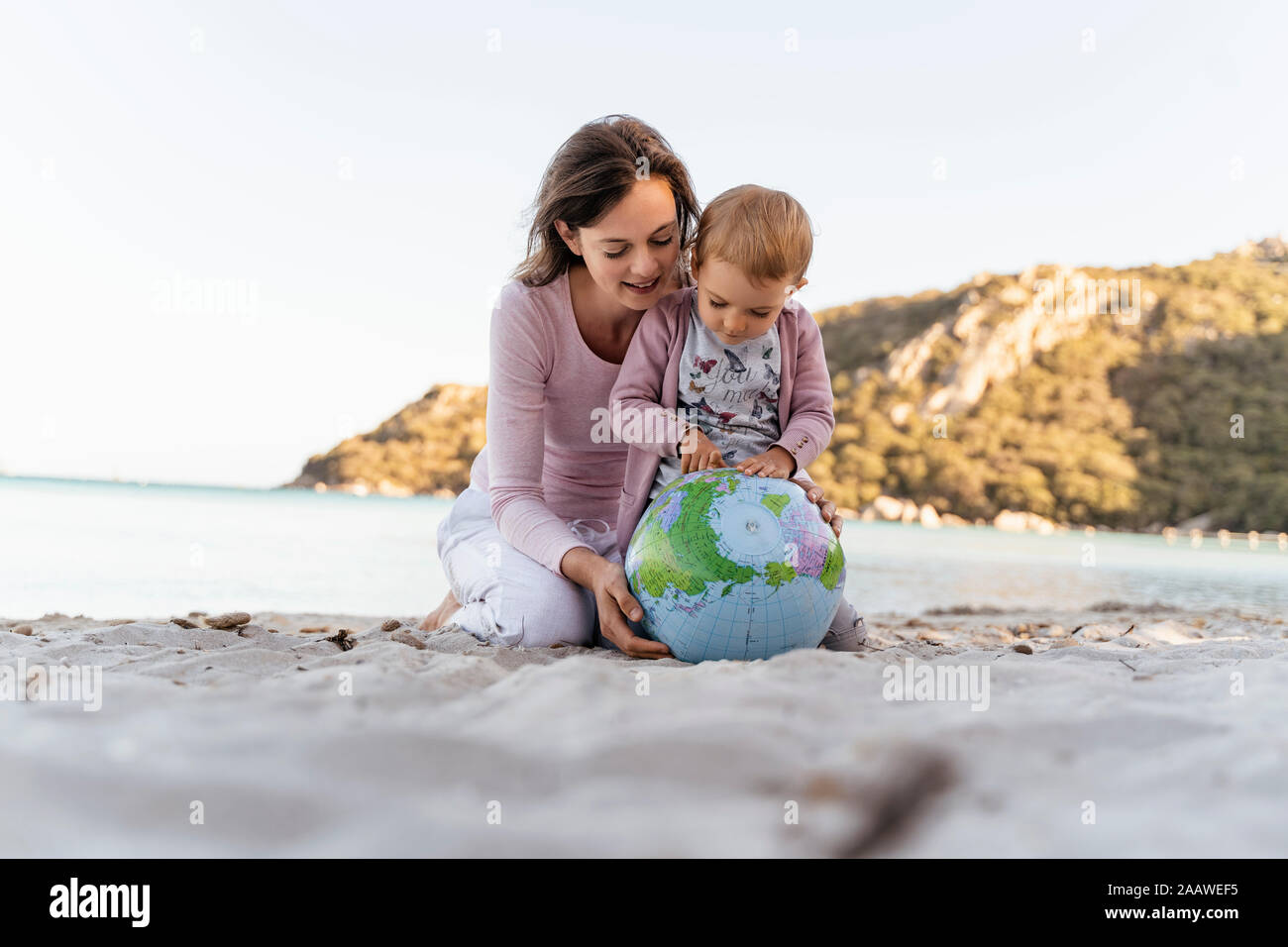 Mother and little daughter looking together at Earth beach ball Stock Photo