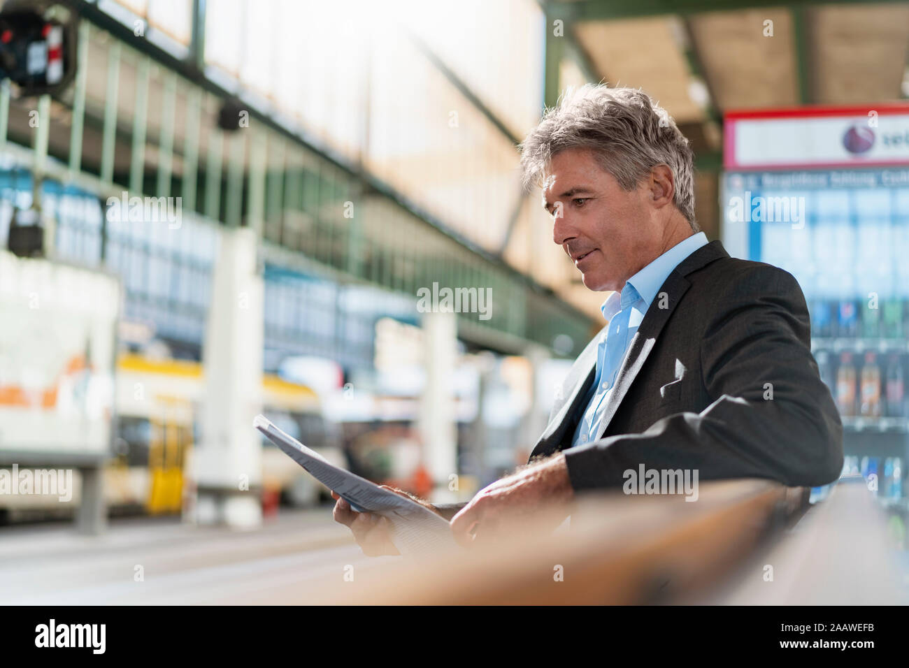 Mature businessman reading newspaper on station platform Stock Photo