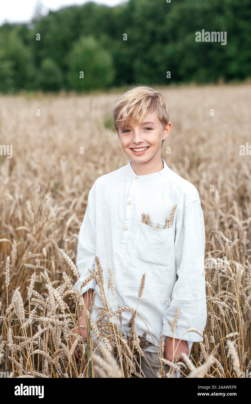 Portrait of happy blond boy standing in an oat field Stock Photo