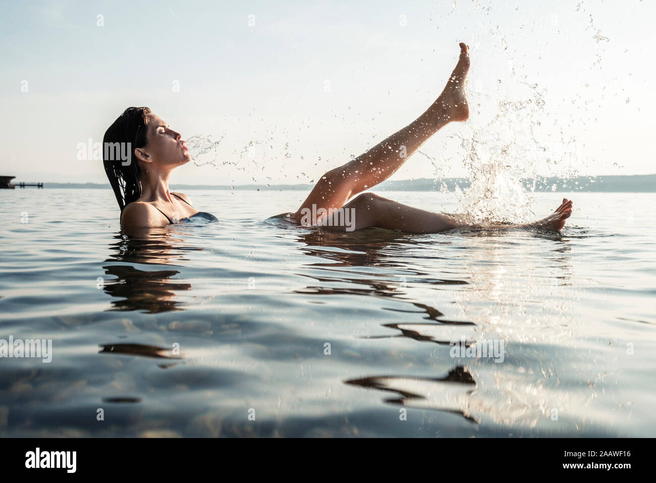 Young woman bathing in Lake Starnberg, splashing with water, Germany Stock Photo