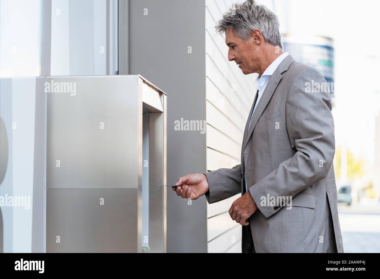 Mature businessman withdrawing money at an ATM Stock Photo