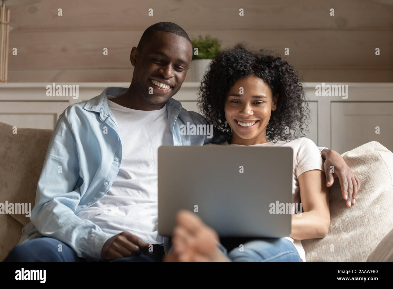 Happy african American couple relax on couch using laptop Stock Photo ...