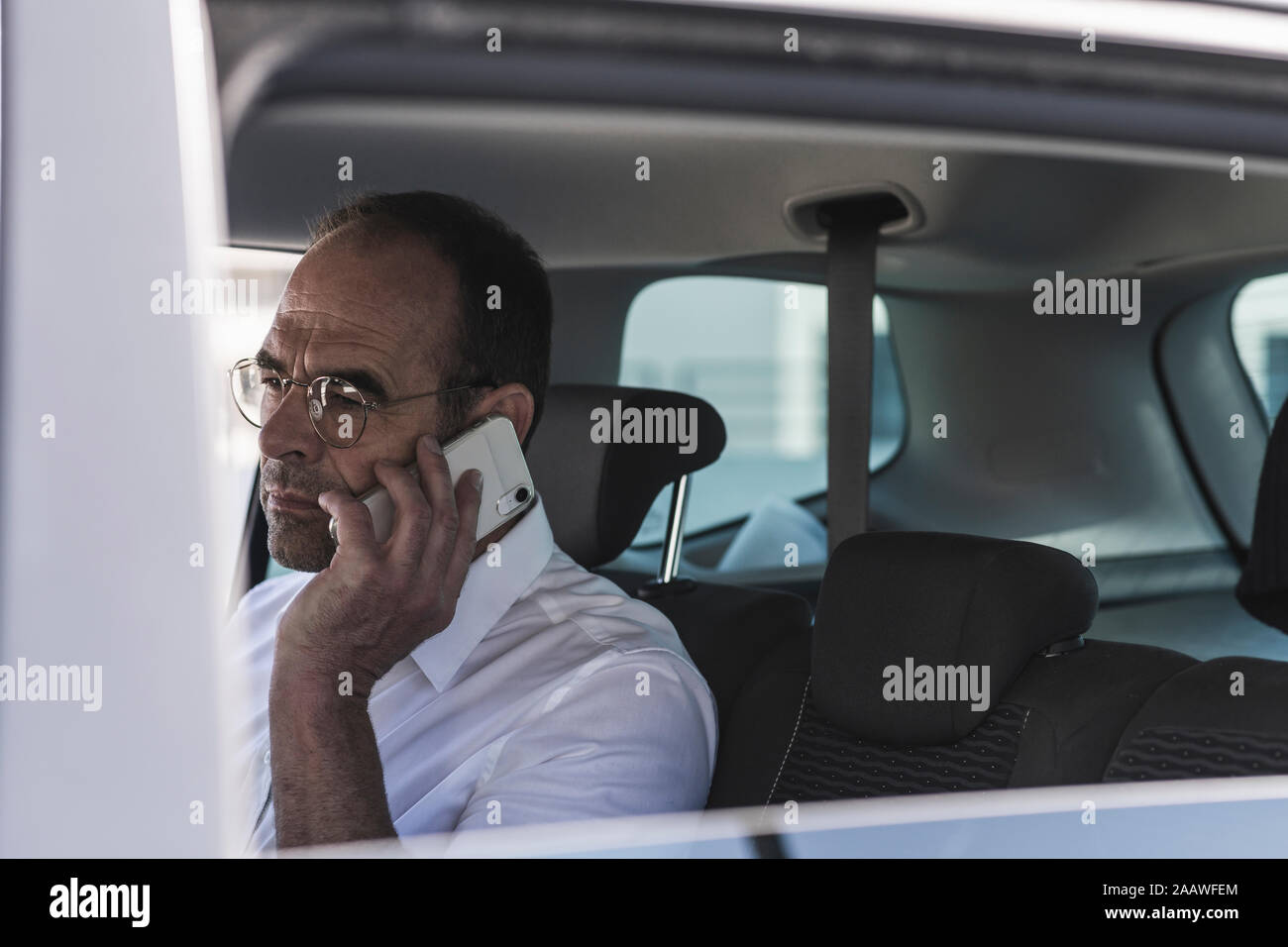 Portrait of mature businessman on the phone in car Stock Photo