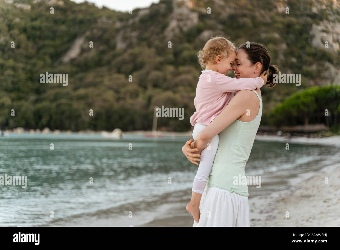 Happy mother carrying her daughter on the beach Stock Photo