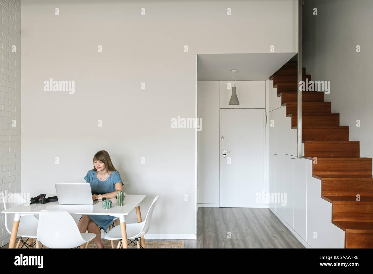 Woman sitting at table working on graphics tablet and laptop Stock Photo