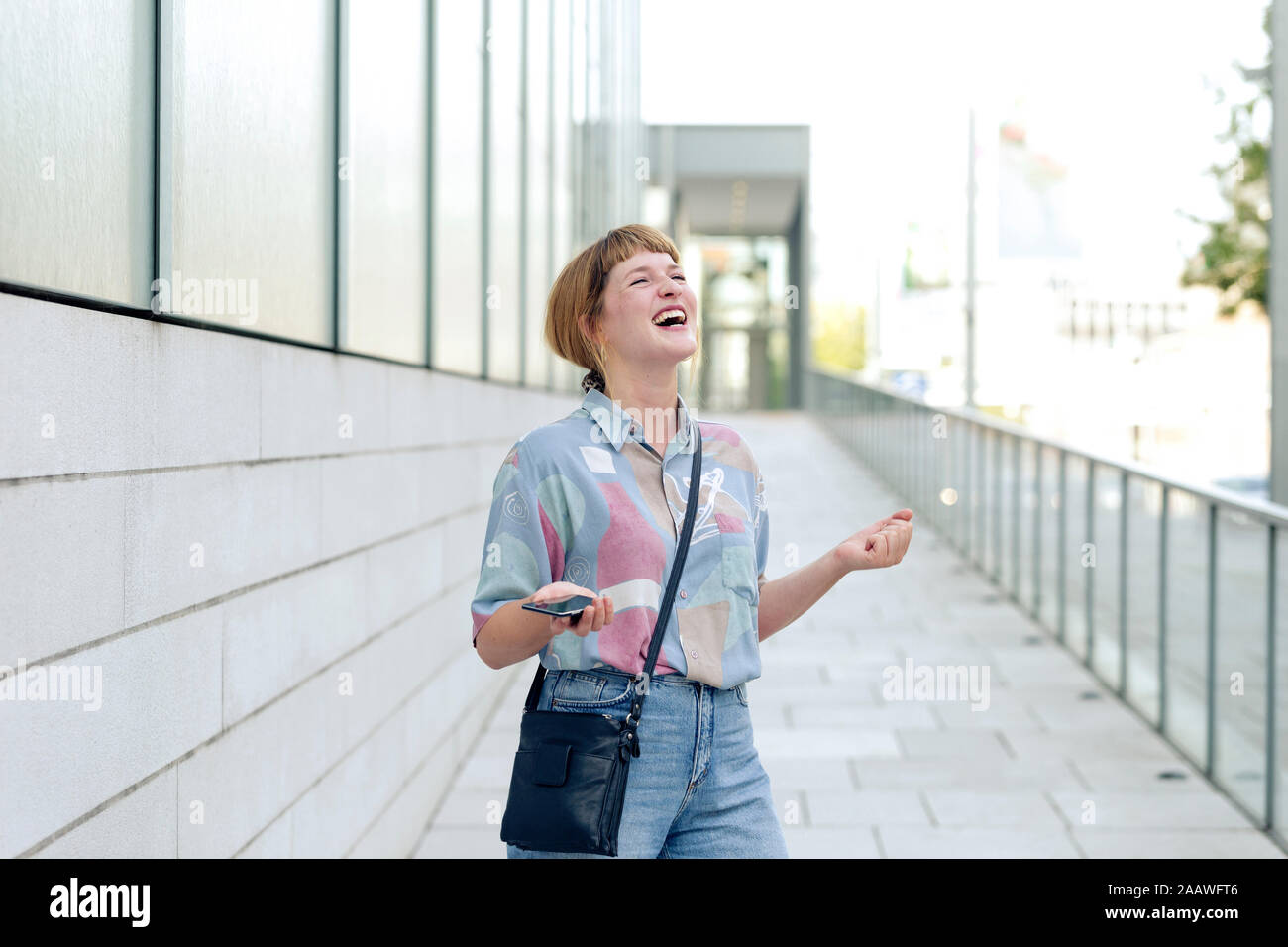 Portrait of young woman with smartphone freaking out Stock Photo