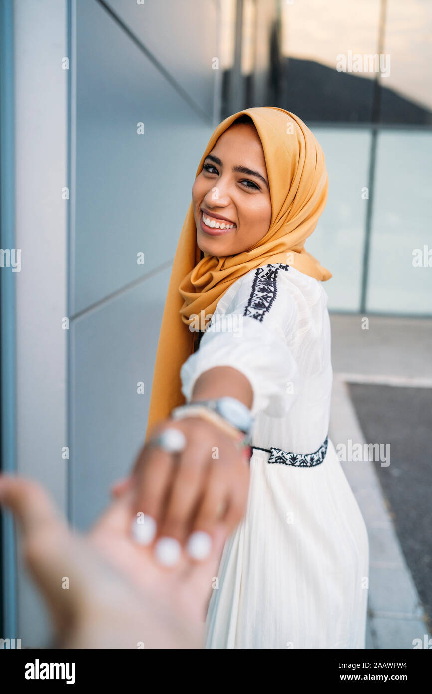 Young muslim woman smiling and taking hand of a man wearing hijab ...