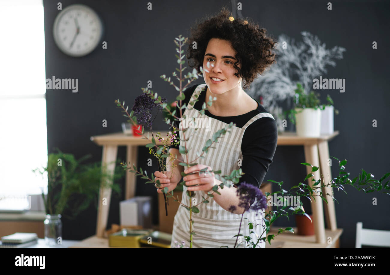 Smiling young woman arranging flowers in a small shop Stock Photo - Alamy