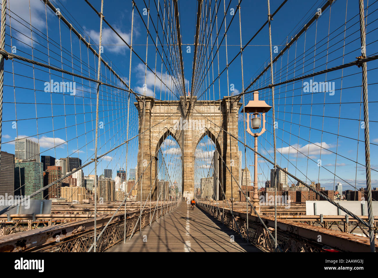 Diminishing perspective of Brooklyn Bridge against blue sky in New York City, USA Stock Photo