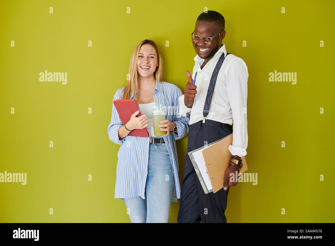 Portrait of happy casual colleagues standing together in front of a green wall Stock Photo