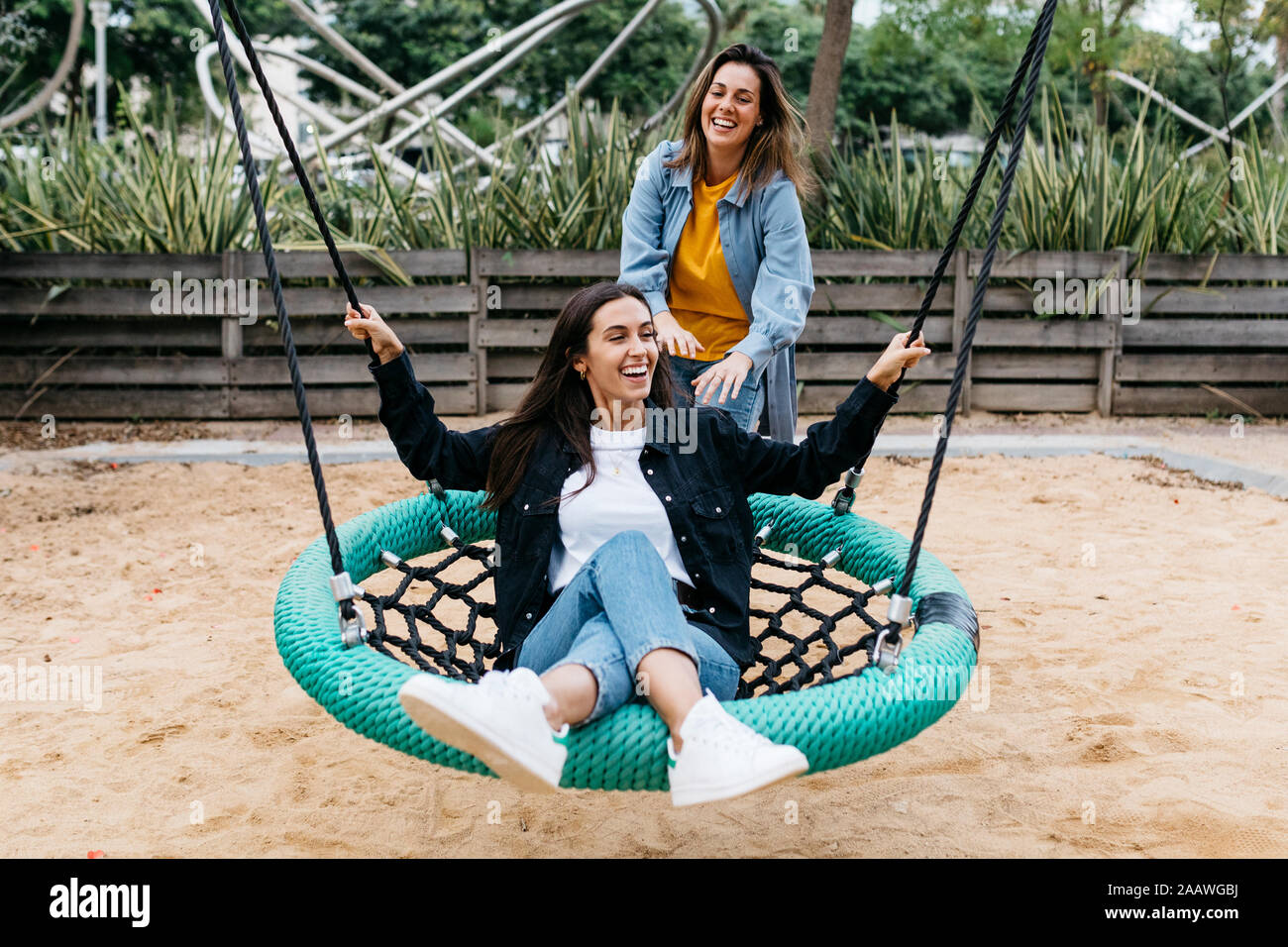 Two friends on playground, woman on a swing Stock Photo