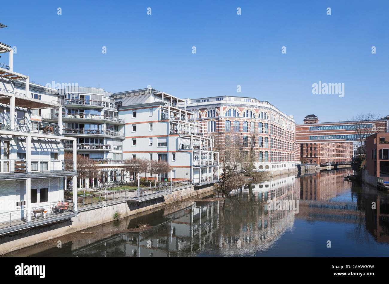 Buildings by White Elster against clear blue sky during sunny day in Saxony, Germany Stock Photo