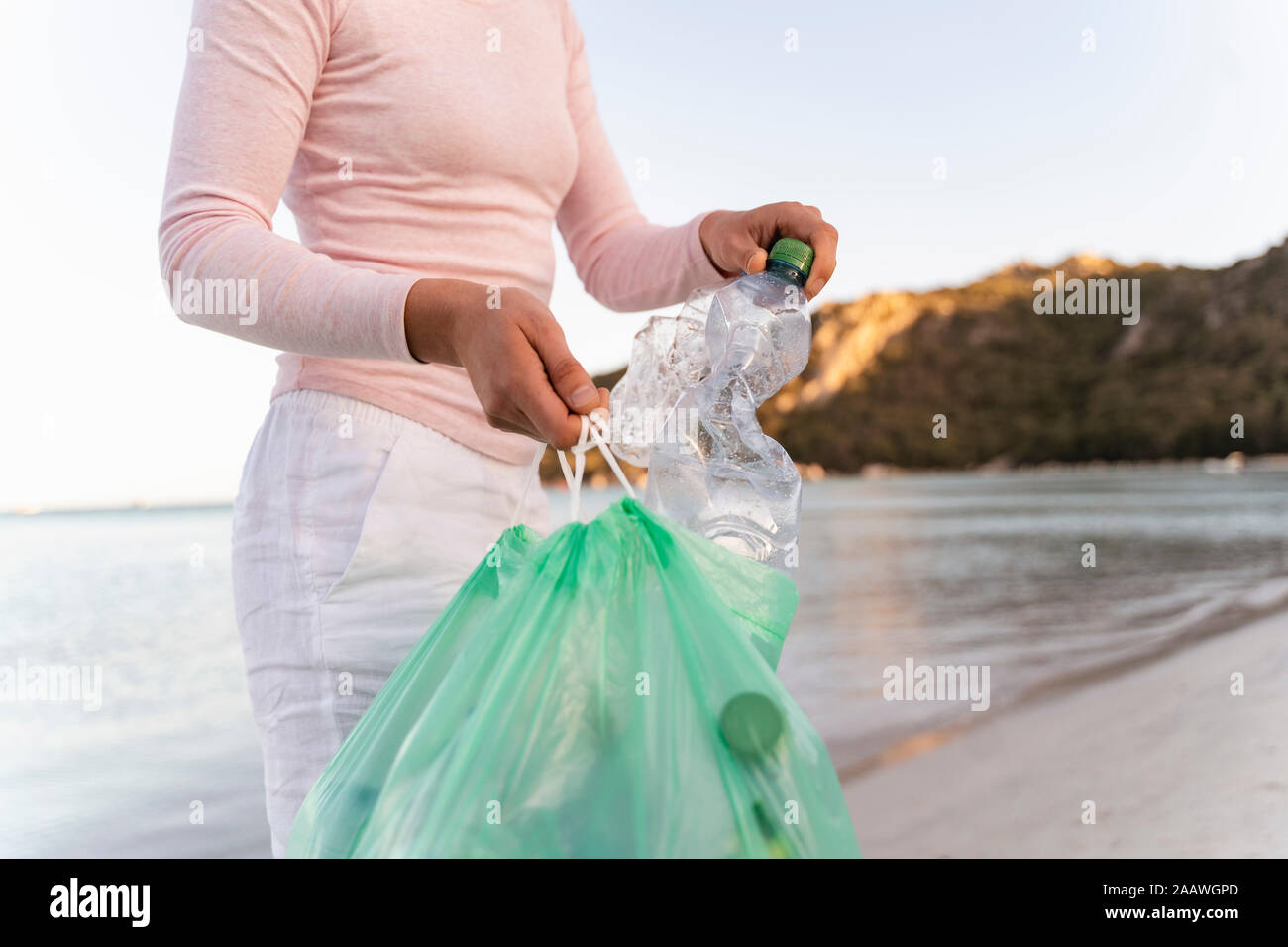 Woman collecting empty plastic bottles  on the beach Stock Photo