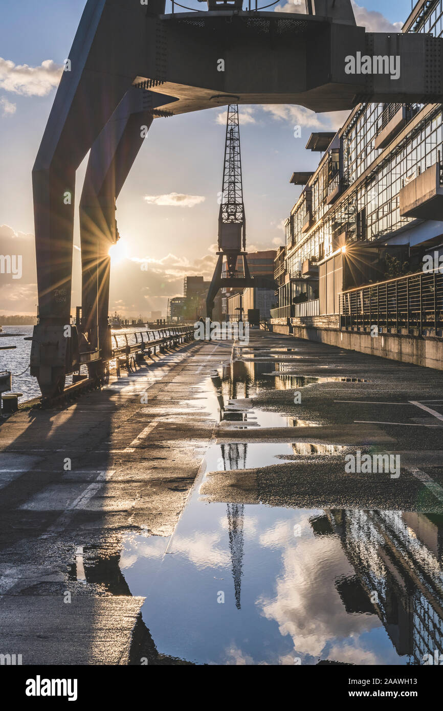 Diminishing perspective of wet footpath by Elbe River during sunset at Hamburg, Germany Stock Photo