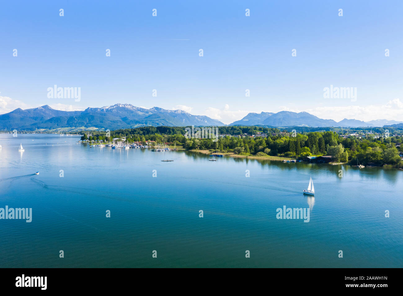 Germany, Bavaria, Prien am Chiemsee, Sailboats sailing near shore of Chiemsee lake with Chiemgau Alps in background Stock Photo