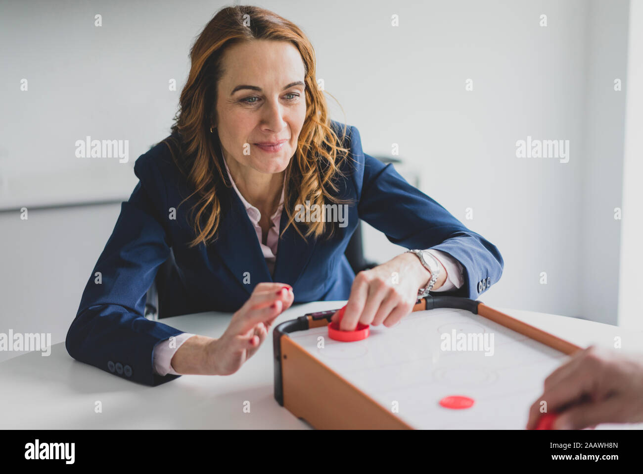 Businesswoman playing air hockey in office Stock Photo