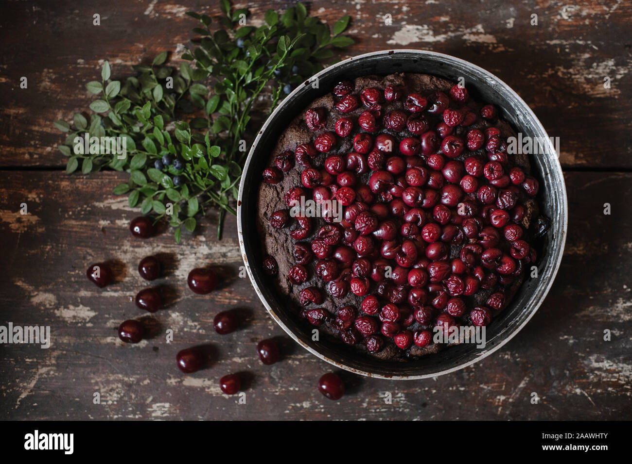 Directly above shot of brownie pie garnished with cherries by herbs on wooden table Stock Photo