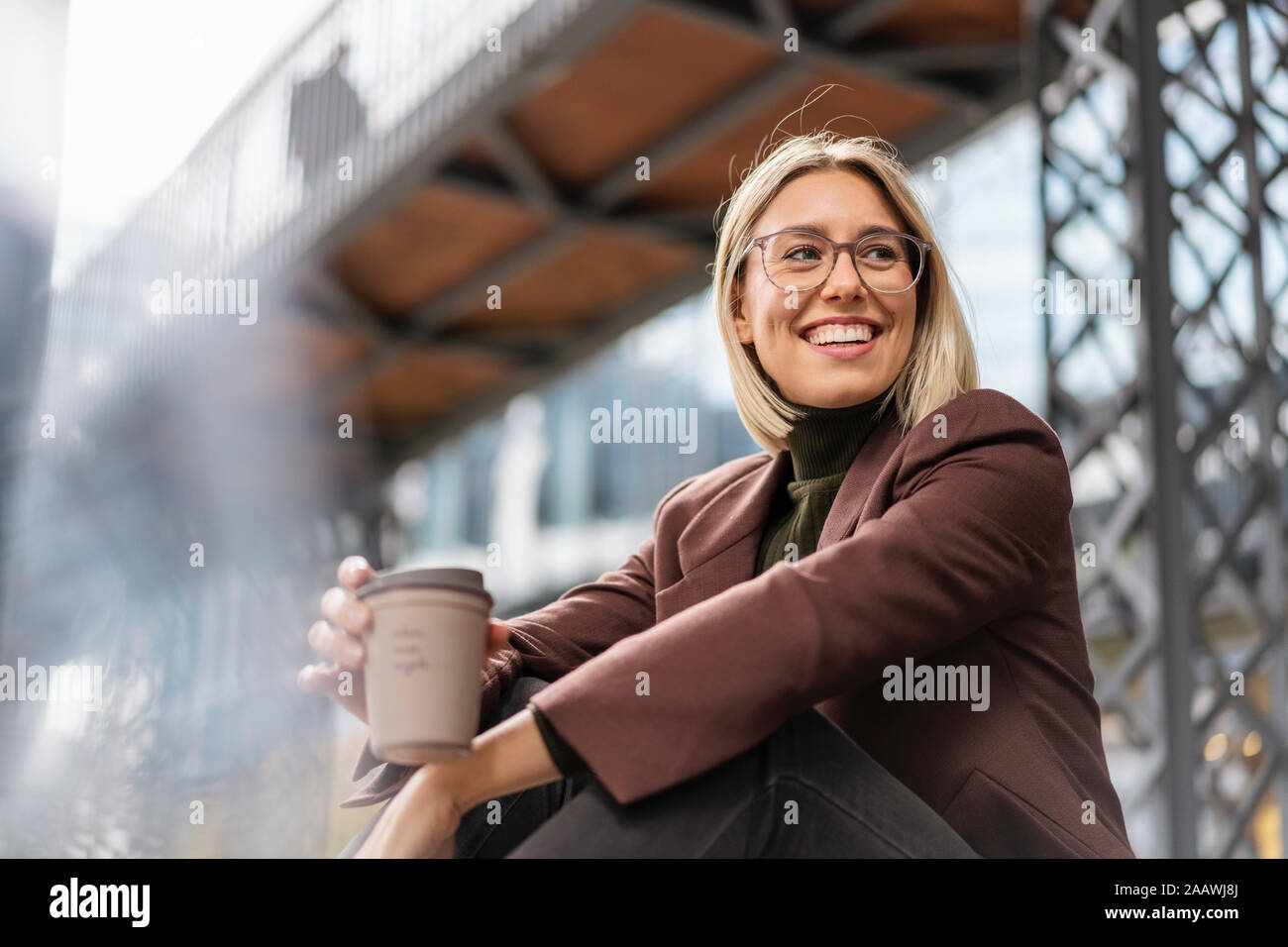 Happy young businesswoman with takeaway coffee in the city Stock Photo
