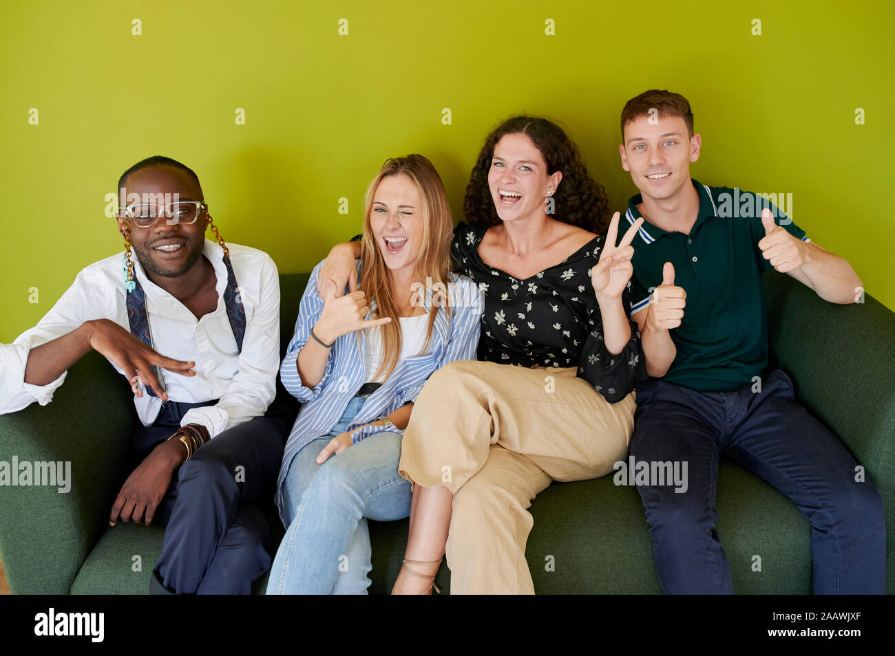 Portrait of happy friends sitting on a sofa Stock Photo