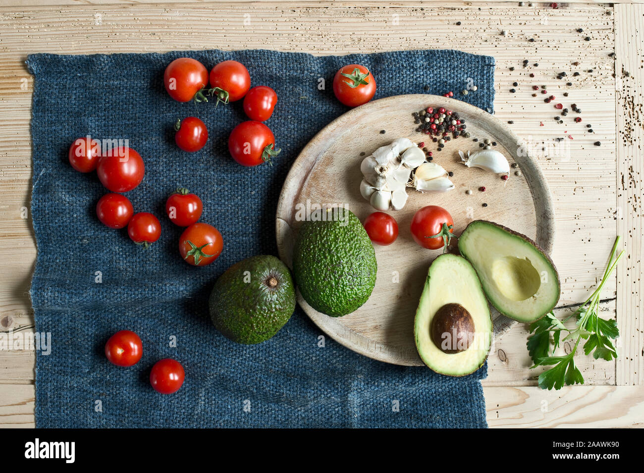 Directly above shot of avocados with tomatoes and spices on wooden table Stock Photo