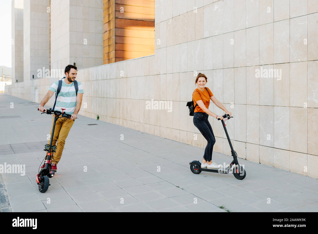 Couple riding electric scooters on pavement Stock Photo Alamy
