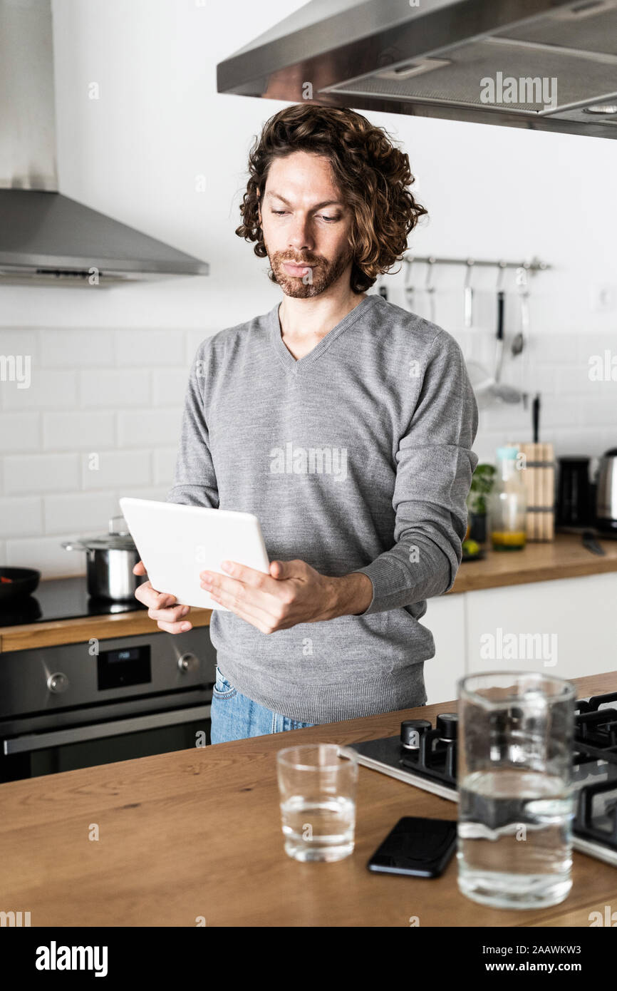 Man using tablet in kitchen at home Stock Photo