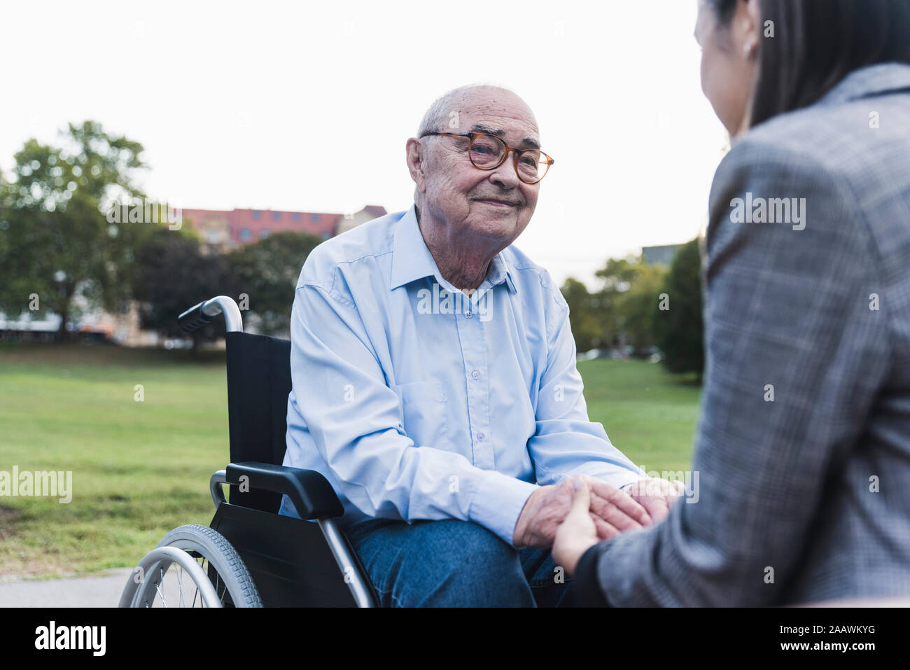 Portrait of senior man sitting in wheel chair holding hands with his granddaughter Stock Photo