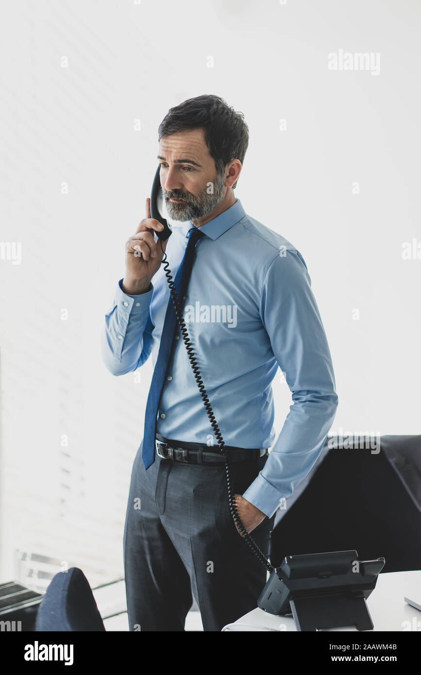 Serious mature businessman on the phone in office Stock Photo