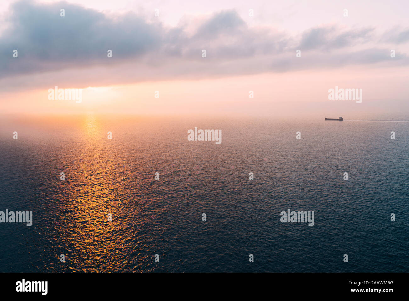 Cargo ship sailing towards sunset at horizon, Mallorca, Spain Stock Photo