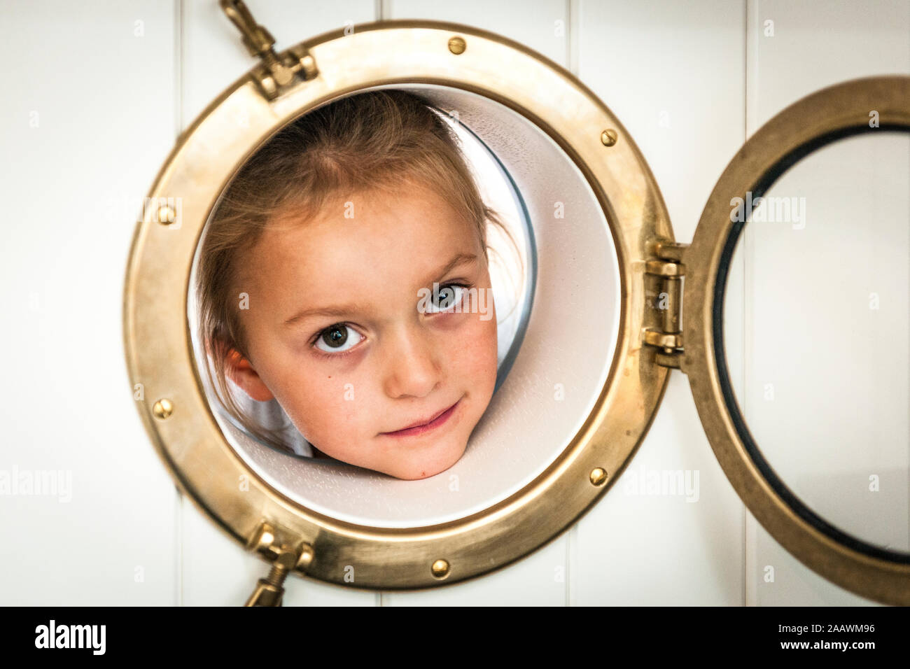 Portrait of girl looking through porthole Stock Photo