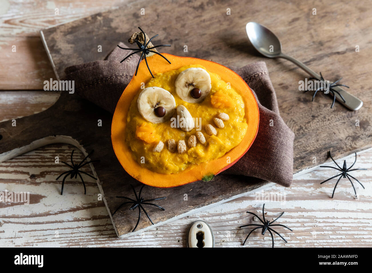 High angle view of pumpkin with anthropomorphic face and decorations on wooden table during Halloween Stock Photo