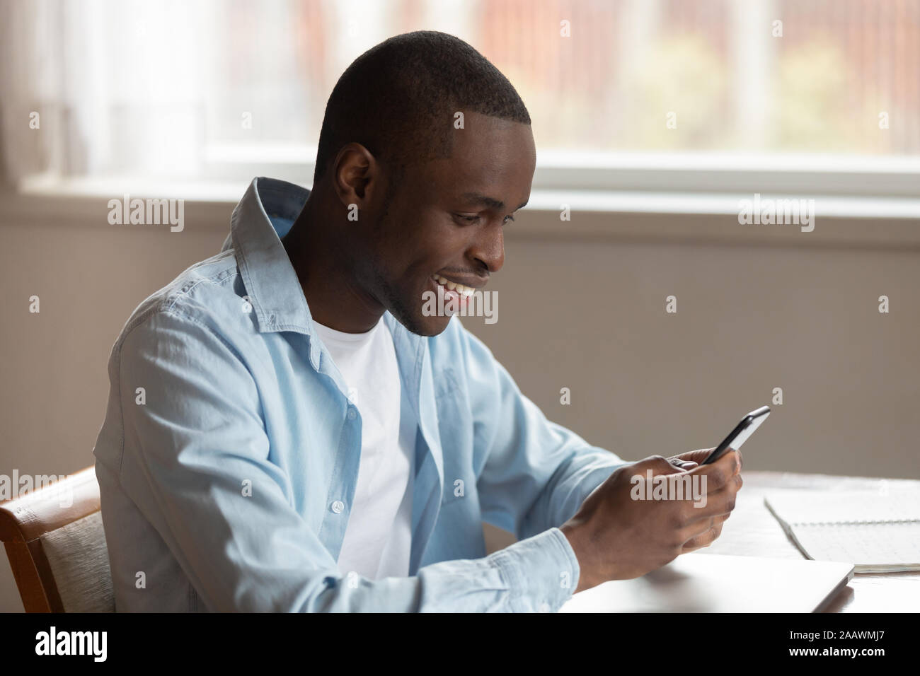 Smiling biracial man using modern smartphone texting Stock Photo