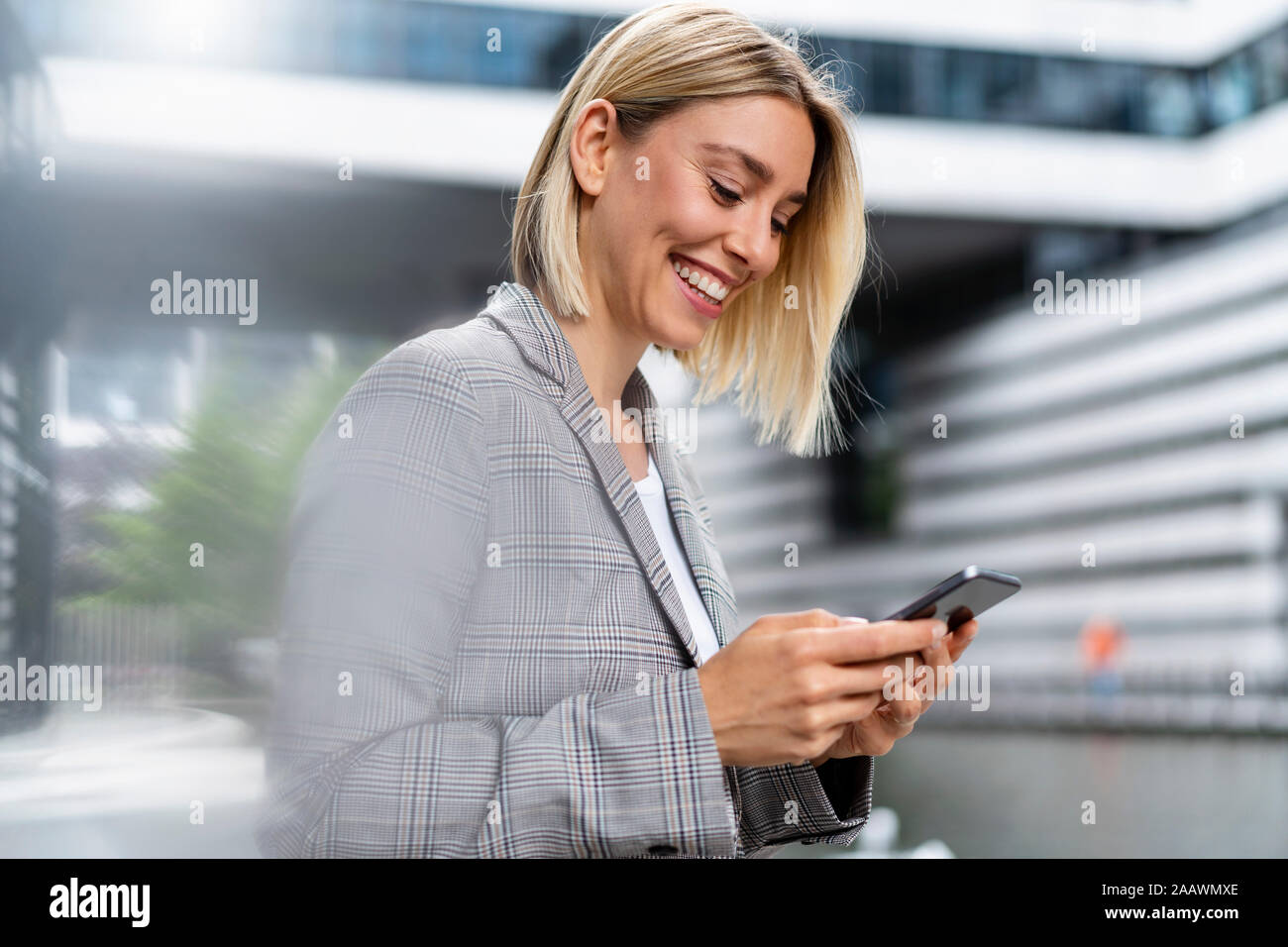 Happy young businesswoman using mobile phone in the city Stock Photo
