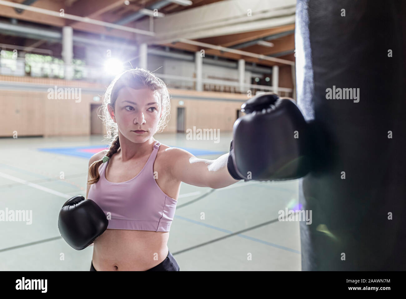 Female boxer practising at punchbag in sports hall Stock Photo