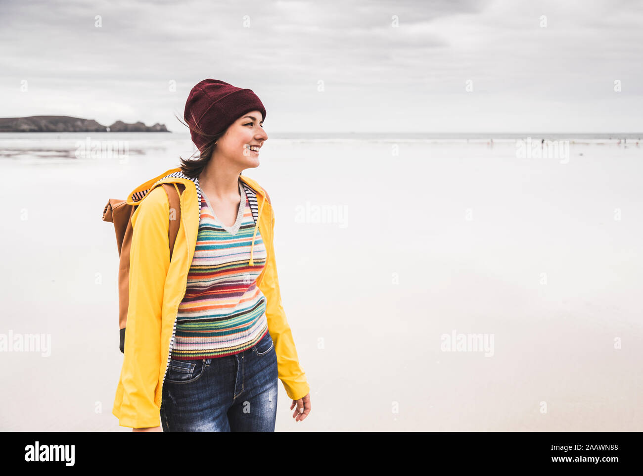 Young woman wearing yellow rain jacket at the beach, Bretagne, France Stock Photo