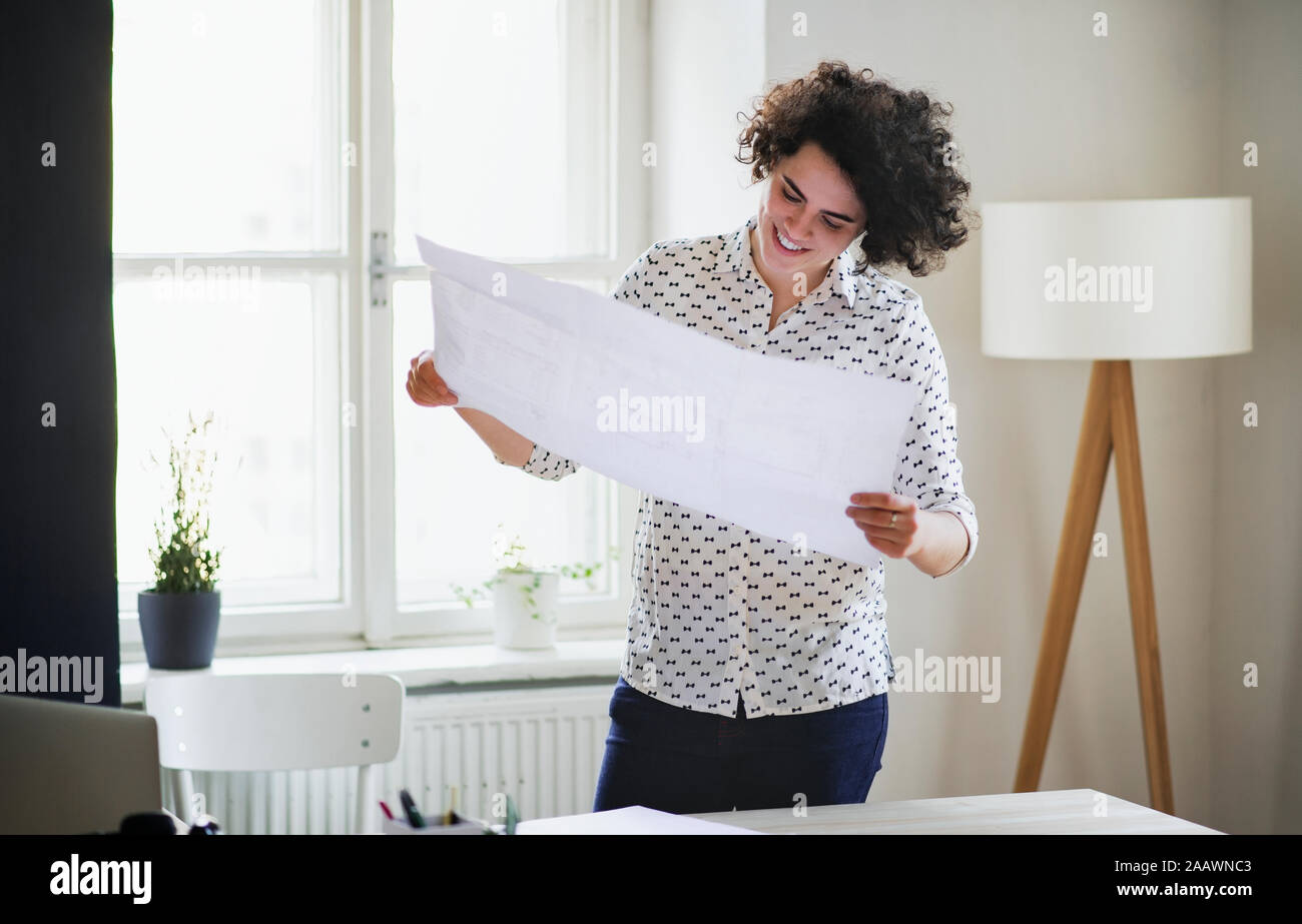 Smiling young woman studying a plan in office Stock Photo