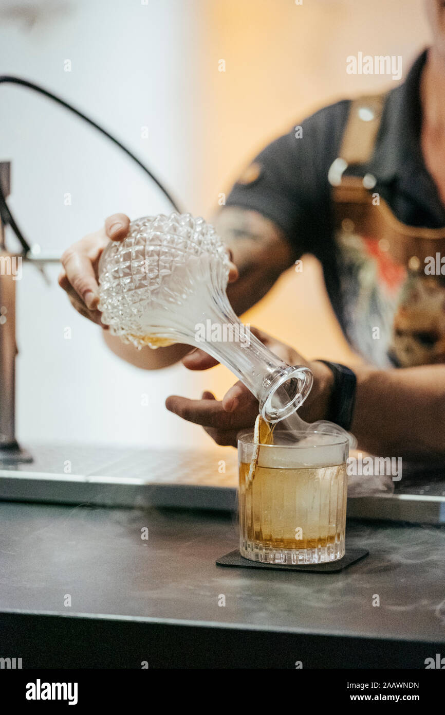 Bartender mixing cocktail in a bar, decanter with steam Stock Photo
