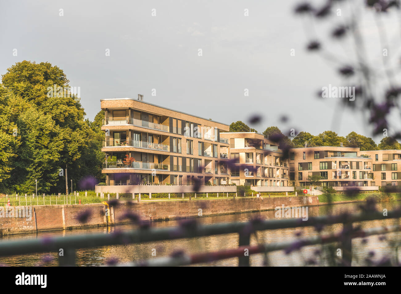 Modern buildings by Trave river against sky in Lübeck, Germany Stock Photo