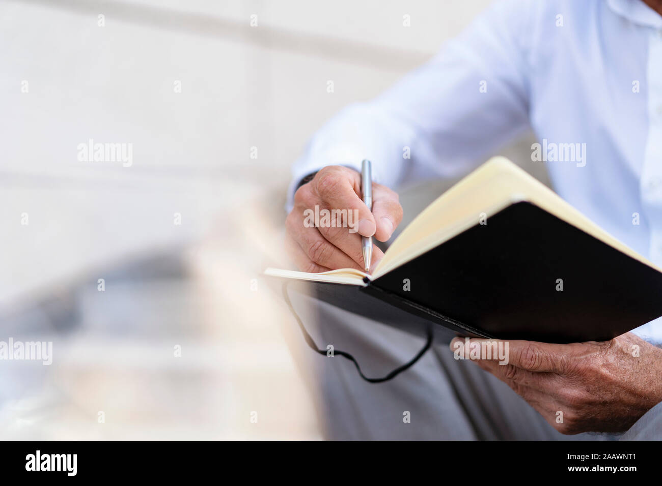 Close-up of businessman sitting on stairs with notebook Stock Photo